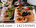 Gourmet Appetizer Platter with Smoked Salmon Caviar Tartlets and Ham Bruschetta on White Ceramic Plates. 142193945