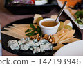 Gourmet cheese platter with blue cheese, hard cheese slices, walnuts, grapes, and honey on a black slate board. 142193946