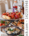 Fresh fruit platter with strawberries and peaches on a tiered metal stand featuring gourmet cheese plates. 142193948