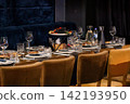 Elegant dining table setting with fresh fruit platter and glassware in a luxury restaurant with blue velvet sofa. 142193950