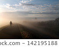 A lone figure walks along the embankment shrouded in morning mist. 142195188