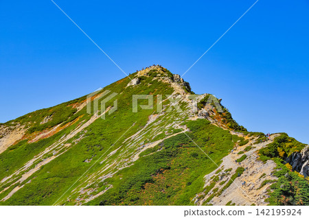 On a clear autumn morning, the view of the main peak, Mt. Karamatsu, from near the Karamatsu Summit Mountain Hut, against a blue sky. On a clear autumn morning, the view of the main peak, Mt. Karamatsu, from near the Karamatsu Summit Mountain Hut, against a blue sky. 142195924