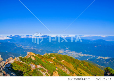 From near the Karamatsu Summit Mountain Hut, you can see the hiking trail you climbed, the town below, and the Myoko mountain range. 142196783