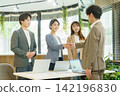Four young Japanese men and women shake hands in an office. Four young Japanese men and women shake hands in an office. 142196830