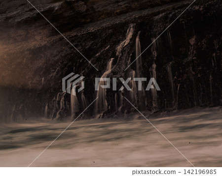 Long exposure photography of silky smooth water cascading over rocky cliff terraces at Klayar Beach (Pantai Klayar) during warm golden hour sunset, Pacitan, East Java, Indonesia. Long exposure photography of silky smooth water cascading over rocky cliff terraces at Klayar Beach (Pantai Klayar) during warm golden hour sunset, Pacitan, East Java, Indonesia. 142196985