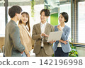 Four young Japanese men and women are talking while looking at their computer screens in an office. Four young Japanese men and women are talking while looking at their computer screens in an office. 142196998