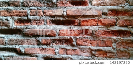 Weathered red brick wall with eroded mortar and spiderwebs. 142197250