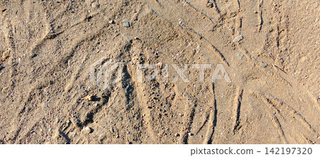 Sandy ground surface with scratches and small pebbles. Sandy ground surface with scratches and small pebbles. 142197320
