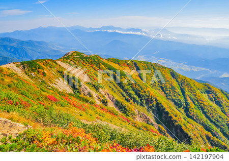 On a clear autumn morning, a view from the hiking trail of Mt. Karamatsu shows the trail we climbed, the town below, and the Myoko mountain range. On a clear autumn morning, a view from the hiking trail of Mt. Karamatsu shows the trail we climbed, the town below, and the Myoko mountain range. 142197904