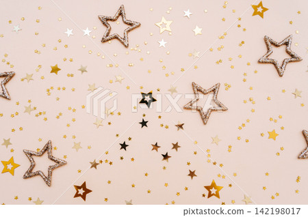 Golden and glittering stars on beige background Golden and glittering stars on beige background 142198017
