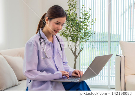 Asian doctor wearing white medical uniform sit at desk using modern laptop Asian doctor wearing white medical uniform sit at desk using modern laptop 142198093