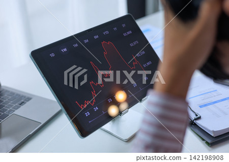 Stressed Investor Looking at Market Crash Stock Chart on Tablet in Office. Stressed Investor Looking at Market Crash Stock Chart on Tablet in Office. 142198908