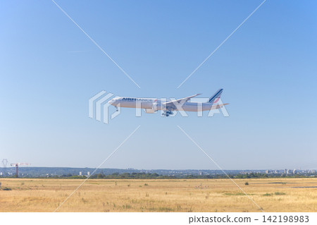 A plane lands at Charles de Gaulle Airport in Paris, France, under clear skies. A plane lands at Charles de Gaulle Airport in Paris, France, under clear skies. 142198983