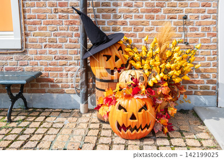 Halloween Jack O lantern pumpkin with witch hat by brick wall Halloween Jack O lantern pumpkin with witch hat by brick wall 142199025