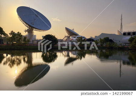 Large satellite dish antenna station with skyline reflection at sunrise Large satellite dish antenna station with skyline reflection at sunrise 142199067