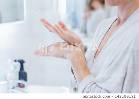 No face middle aged woman Applying Hand Cream in bathroom during morning routine, Dry Skin Remedy. Skin hydrating. Cosmetic spa procedures. Beauty self-care at home. Home Beauty treatment routine 142199151