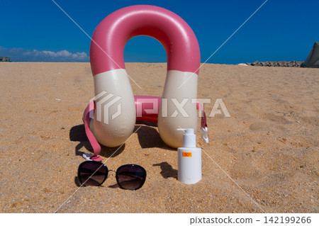 Sunscreen SPF50, sunglasses and swim ring are on the sand Sunscreen SPF50, sunglasses and swim ring are on the sand 142199266