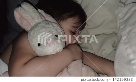 Cute little toddler girl sleeping in bed holding favorite plush white bunny toy close close up cozy bedroom night stock photo Cute little toddler girl sleeping in bed holding favorite plush white bunny toy close close up cozy bedroom night stock photo 142199388