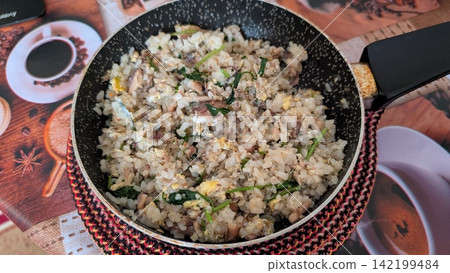 Homemade fried rice with fish flakes and green herbs in a small frying pan Homemade fried rice with fish flakes and green herbs in a small frying pan 142199484