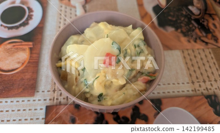 Homemade potato and shrimp gratin with fresh herbs in a small bowl 142199485