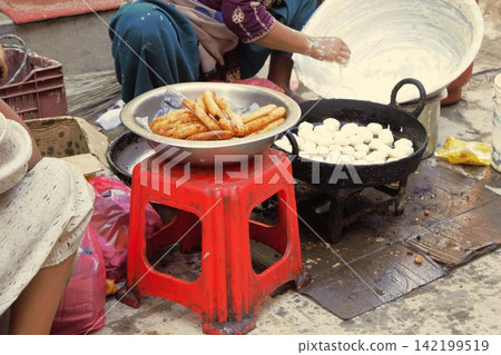 A scene of people preparing fried sweets at a street market (Kathmandu, Nepal) A scene of people preparing fried sweets at a street market (Kathmandu, Nepal) 142199519