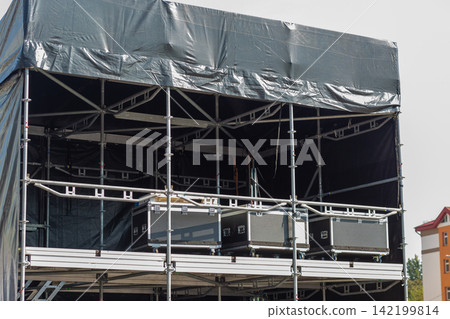 Back of a temporary outdoor concert stage covered with black tarpaulin 142199814
