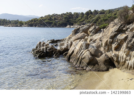 Rocky shoreline with crystal clear turquoise sea water and beach 142199863