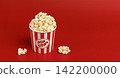 Fresh popcorn in paper cup on red background. Movie night and entertainment snack concept. 142200000
