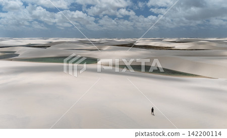 空拍照片顯示,倫索伊斯·馬拉赫塞斯 (Lençóis Maranhenses) 的一個小人物站在雲層覆蓋的白色沙丘上。 空拍照片顯示,倫索伊斯·馬拉赫塞斯 (Lençóis Maranhenses) 的一個小人物站在雲層覆蓋的白色沙丘上。 142200114