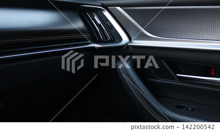 Air vent, door opening and locking handle inside a premium car with leather interior trim. Textures Of Leather Upholstery And Aluminum Details On Handle Of Car Door Air vent, door opening and locking handle inside a premium car with leather interior trim. Textures Of Leather Upholstery And Aluminum Details On Handle Of Car Door 142200542