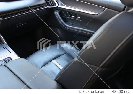 The passenger seat inside the car is covered in expensive leather with perforations for cooling and heating. Leather trimming and car interior upholstery 142200552