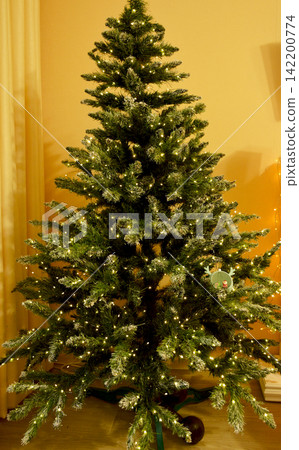 A Christmas tree decorated with toys stands in the corner of the room 142200774