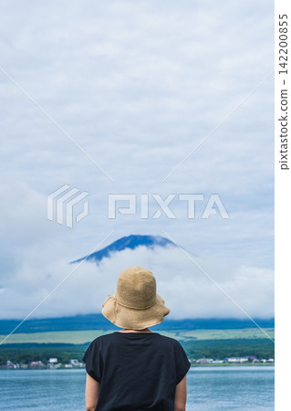 A woman with her back to the camera and Mount Fuji | A woman gazing at Mount Fuji in summer from the shore of Lake Yamanaka A woman with her back to the camera and Mount Fuji | A woman gazing at Mount Fuji in summer from the shore of Lake Yamanaka 142200855