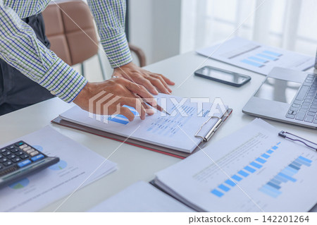 Professional financial advisor auditing company profit graph statistics paper report at desk in modern office. Professional financial advisor auditing company profit graph statistics paper report at desk in modern office. 142201264