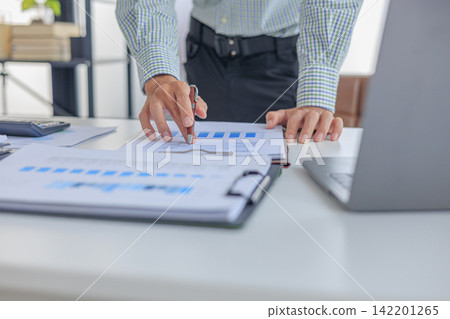 Businessman analyzing financial report data graph chart on clipboard at desk in office. 142201265
