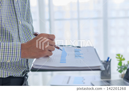 Businessman analyzing financial report data graph chart on clipboard at desk in office. Businessman analyzing financial report data graph chart on clipboard at desk in office. 142201268