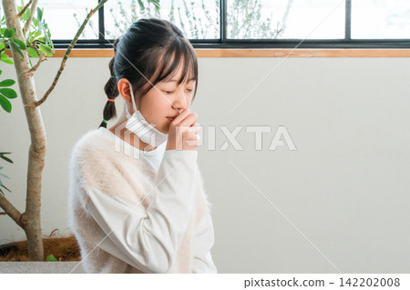 身體不適的小學和國中女生在沙發上咳嗽 身體不適的小學和國中女生在沙發上咳嗽 142202008
