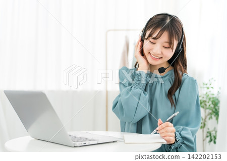 Young Asian businesswoman wearing a headset working in front of a computer Young Asian businesswoman wearing a headset working in front of a computer 142202153