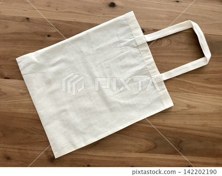 A white eco-bag placed on a wooden table A white eco-bag placed on a wooden table 142202190