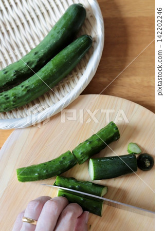 Fresh cucumbers from the home garden being cut on a cypress cutting board. Fresh cucumbers from the home garden being cut on a cypress cutting board. 142202246