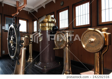 Antique brass steering wheel and navigation instruments lined up in the bridge of the battleship Mikasa. Antique brass steering wheel and navigation instruments lined up in the bridge of the battleship Mikasa. 142202316