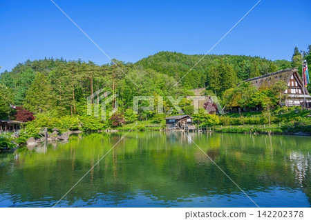 飛驒高山的合掌造房屋,周圍環繞著蔥鬱的綠植和美麗的池塘景色。 飛驒高山的合掌造房屋,周圍環繞著蔥鬱的綠植和美麗的池塘景色。 142202378