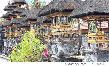 Pura Besakih temple complex showcases a row of ancient Balinese shrines with traditional thatched roofs and elaborately carved golden details Pura Besakih temple complex showcases a row of ancient Balinese shrines with traditional thatched roofs and elaborately carved golden details 142202380