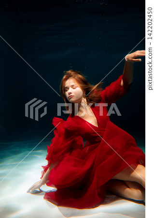 Ethereal figure in crimson attire swimming near pool bottom silently Ethereal figure in crimson attire swimming near pool bottom silently 142202450