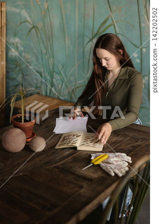 Female artist engaged in plant drawing using watercolors and ink Female artist engaged in plant drawing using watercolors and ink 142202502