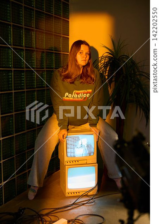 Teenage girl in cozy room viewing antique television screen Teenage girl in cozy room viewing antique television screen 142202550