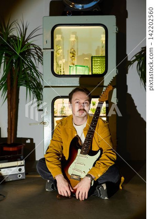 Serene scene with guitarist surrounded by atmospheric shadows and glow Serene scene with guitarist surrounded by atmospheric shadows and glow 142202560