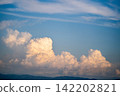 Cumulonimbus clouds illuminated by the setting sun spreading across the summer sky 142202821