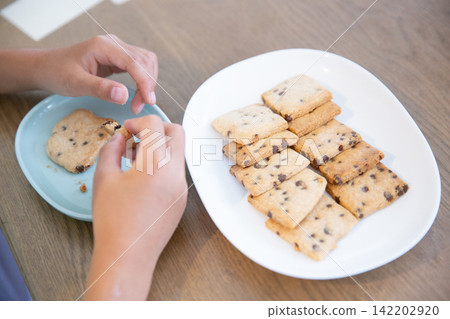 A child eating homemade rice flour chocolate chip cookies. A child eating homemade rice flour chocolate chip cookies. 142202920