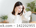 A woman checks her hairline in the mirror. 142202955